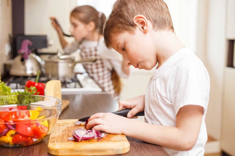 La Guilde Culinaire camps d'été.  Photo d'enfant qui cuisine. Découpe de légumes.